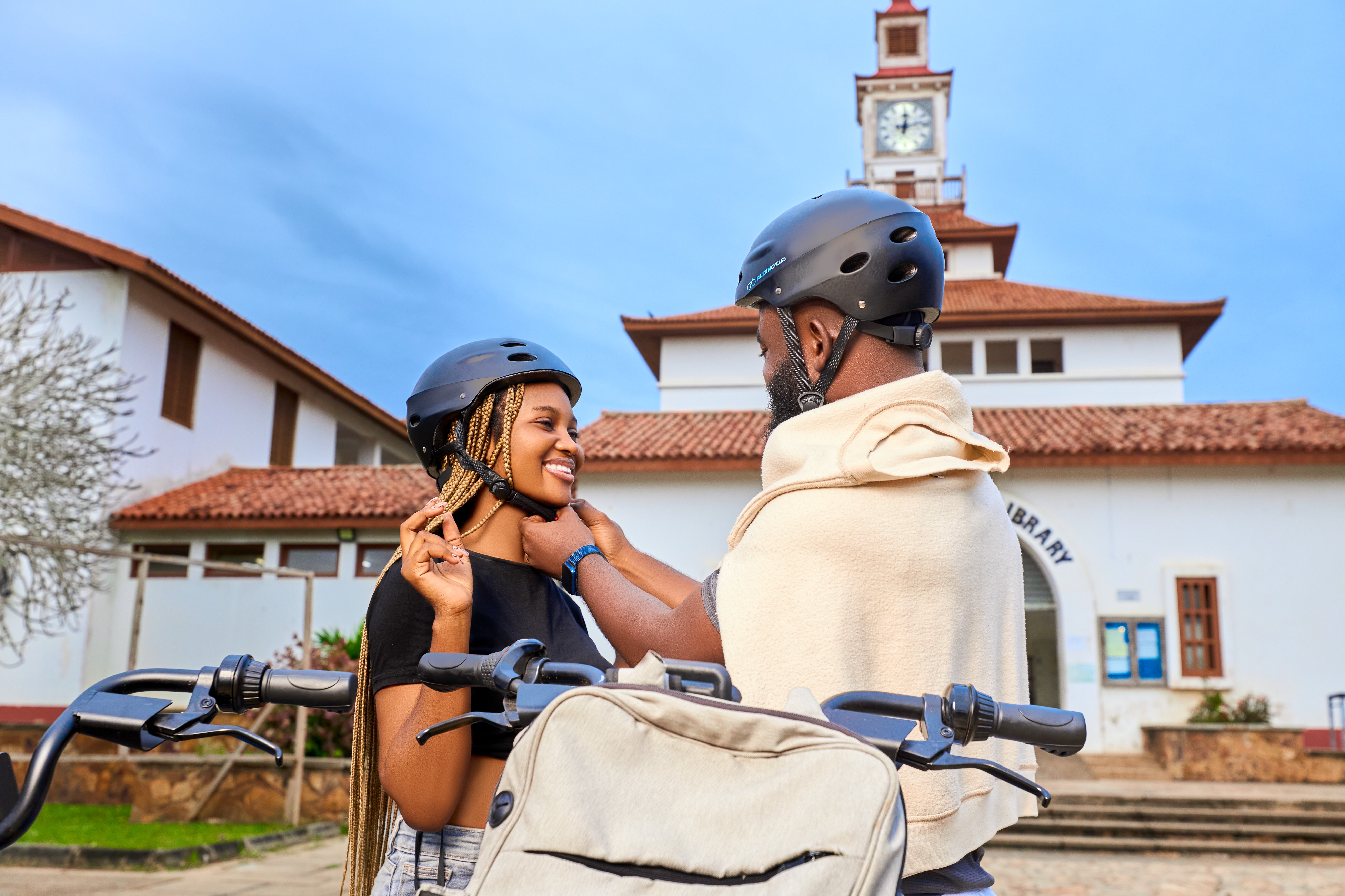 Lady wearing a helmet with the help of a guy